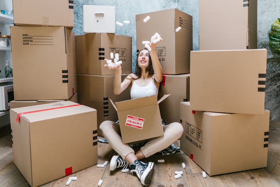 Close-up image of two brown cardboard boxes placed on a wooden floor inside a property. The top box has handwritten red marker text reading 'STUFF' with a small smiley face below, while the bottom box